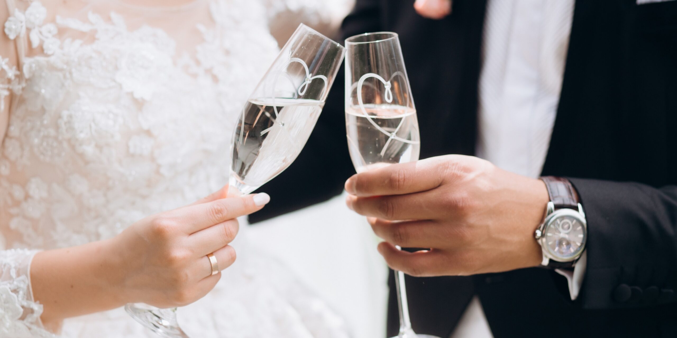 Groom with bride are knocking glasses with champagne